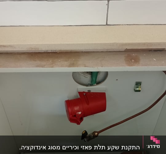 שקע חשמלי אדום וצינור נחושת בארון חשמל